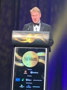Managing director and founding partner Neill Brennan standing at the podium speaking to crowd of business people at awards event